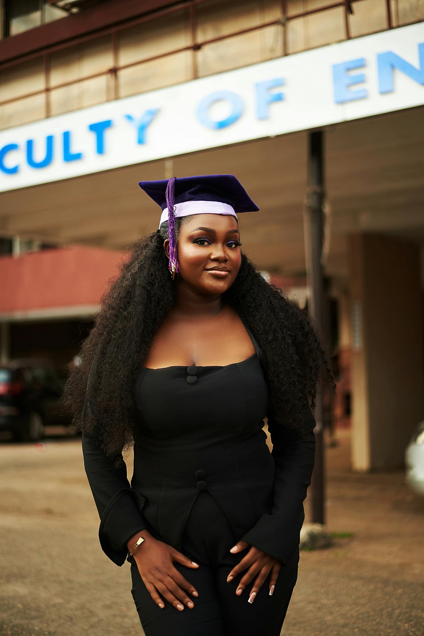 Proud graduate in cap and gown outside the Faculty of Engineering building.